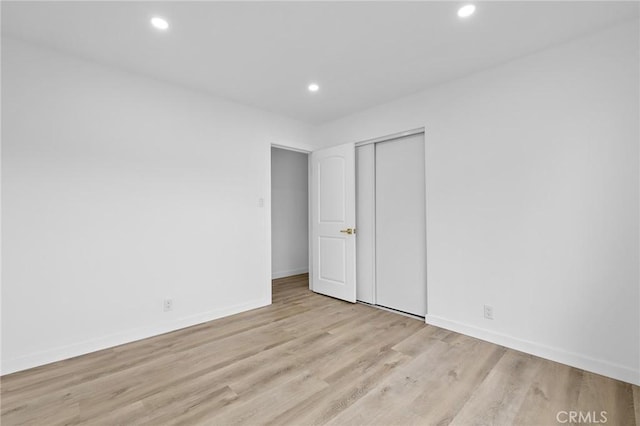 unfurnished bedroom featuring a closet, recessed lighting, baseboards, and wood finished floors