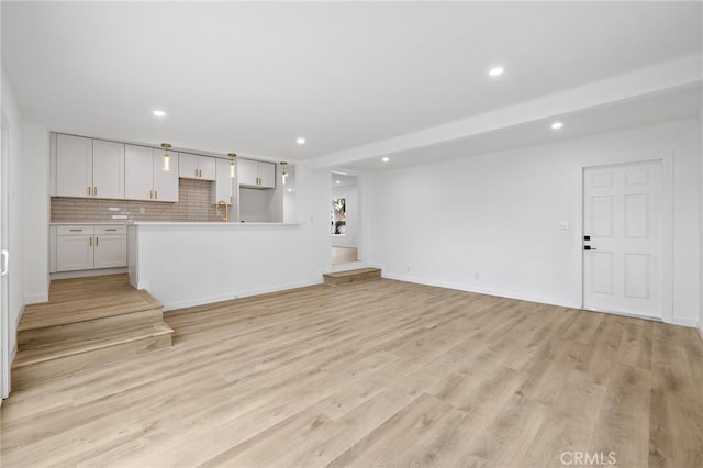 unfurnished living room with recessed lighting, light wood-type flooring, and baseboards