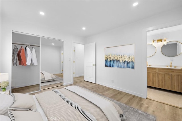 bedroom featuring a closet, recessed lighting, light wood-type flooring, and a sink