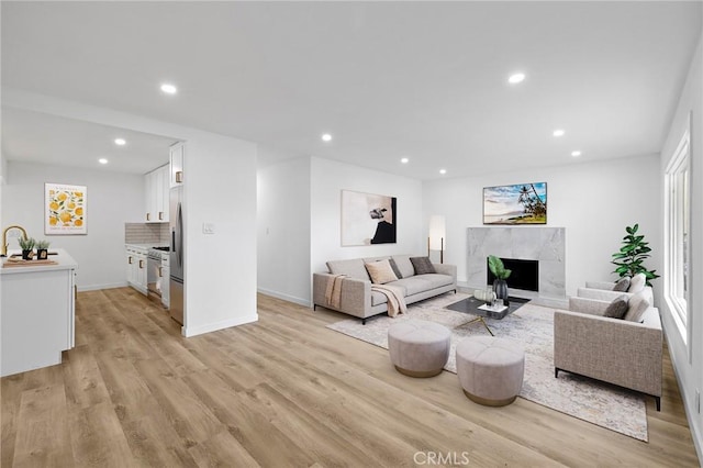 living area featuring recessed lighting, baseboards, light wood-style floors, and a premium fireplace