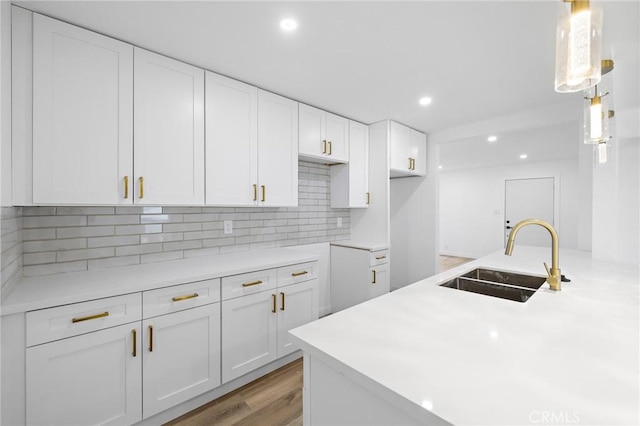 kitchen featuring tasteful backsplash, recessed lighting, white cabinets, and a sink