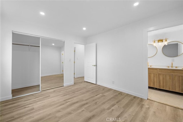 unfurnished bedroom featuring ensuite bath, recessed lighting, light wood-type flooring, and a closet