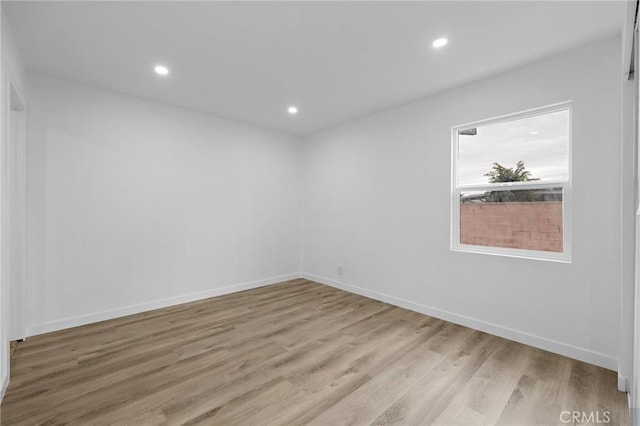 unfurnished room featuring recessed lighting, light wood-type flooring, and baseboards