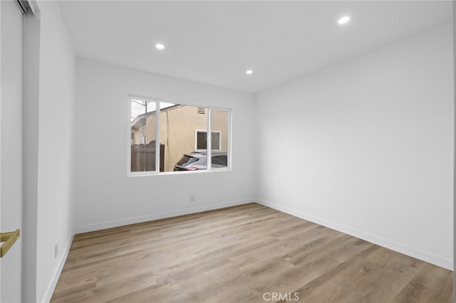 spare room featuring recessed lighting, baseboards, and wood finished floors