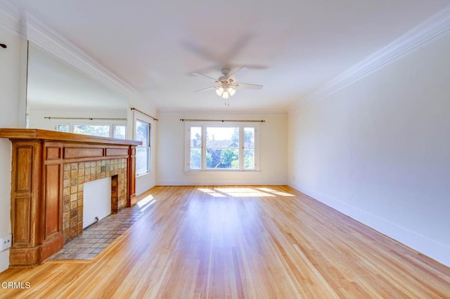 unfurnished living room featuring baseboards, ornamental molding, light wood-style flooring, a fireplace, and a ceiling fan