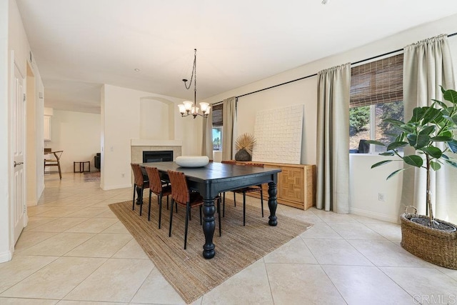 dining area with light tile patterned floors, a chandelier, and a fireplace