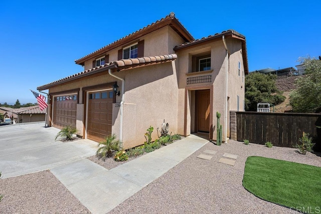 mediterranean / spanish home featuring stucco siding, fence, concrete driveway, and a tile roof