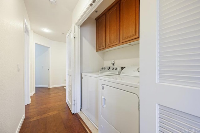 washroom with washing machine and clothes dryer, cabinet space, dark wood-type flooring, and baseboards