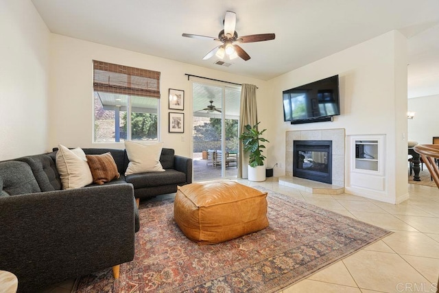 living room with tile patterned floors, visible vents, a ceiling fan, and a tiled fireplace