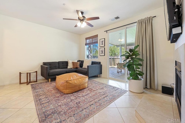 living area featuring light tile patterned floors, visible vents, a fireplace, and ceiling fan