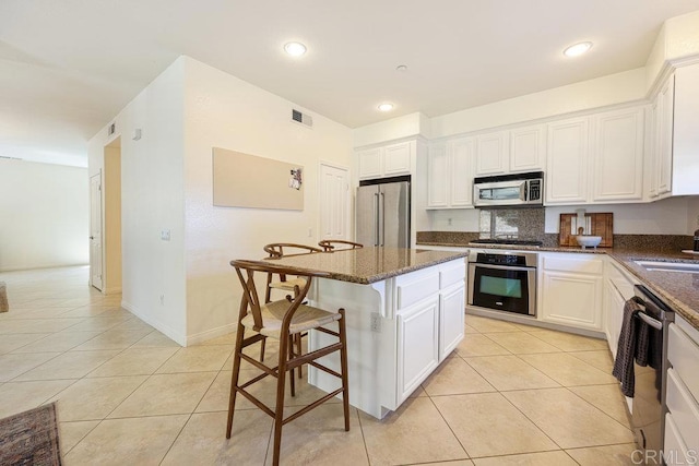 kitchen with a kitchen bar, light tile patterned floors, visible vents, and appliances with stainless steel finishes