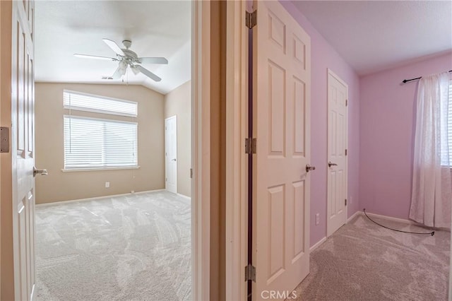 hallway with light carpet, a healthy amount of sunlight, and lofted ceiling