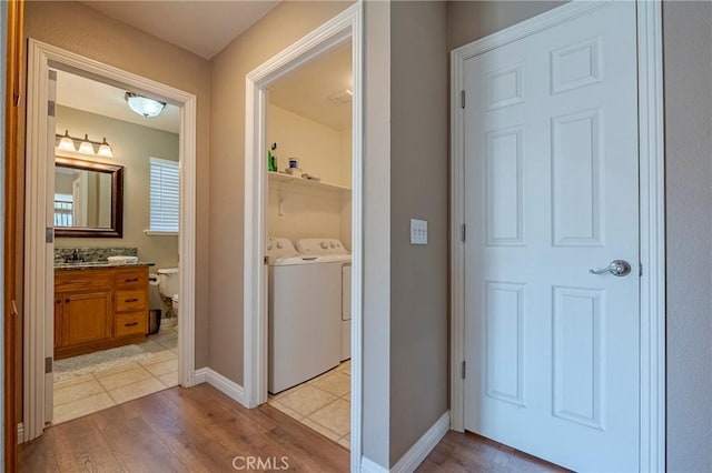 interior space with a sink, baseboards, independent washer and dryer, and light wood-type flooring