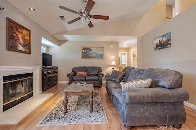 living room featuring lofted ceiling, wood finished floors, visible vents, and baseboards