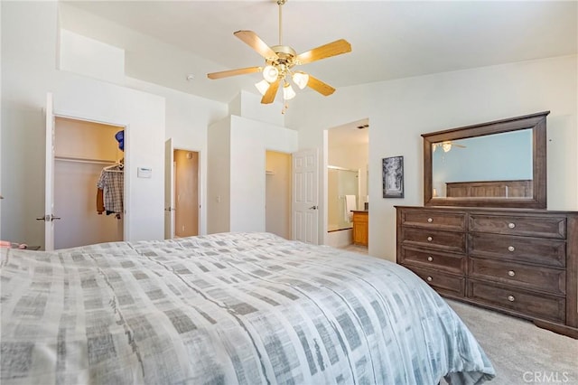 bedroom with a walk in closet, a ceiling fan, ensuite bath, carpet floors, and lofted ceiling