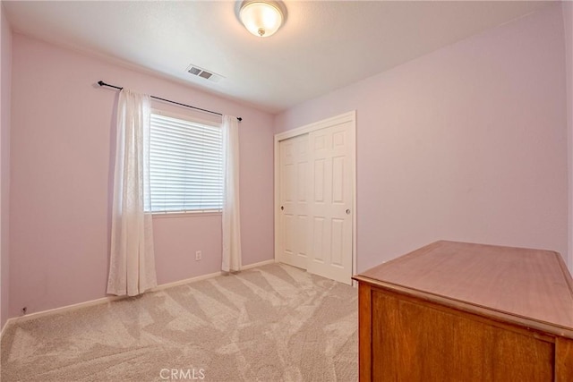 unfurnished bedroom with light colored carpet, visible vents, a closet, and baseboards