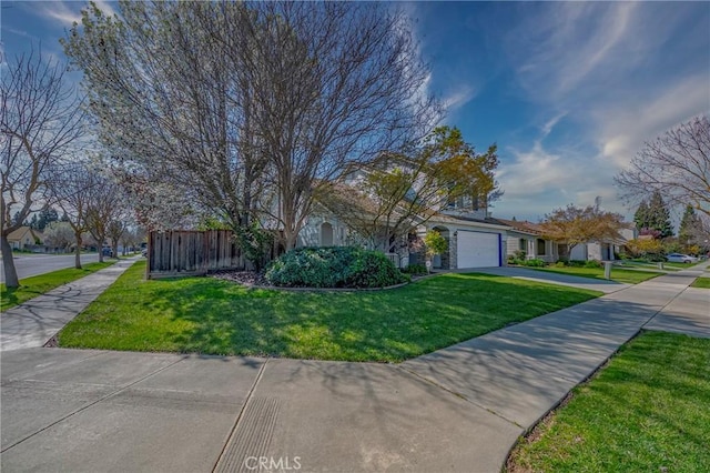 view of front facade with a front lawn, fence, a garage, and driveway