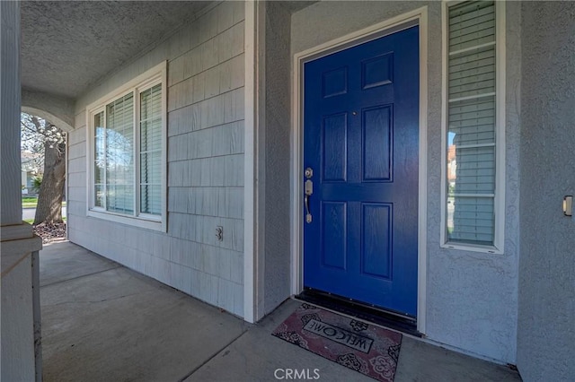 entrance to property featuring a porch and stucco siding