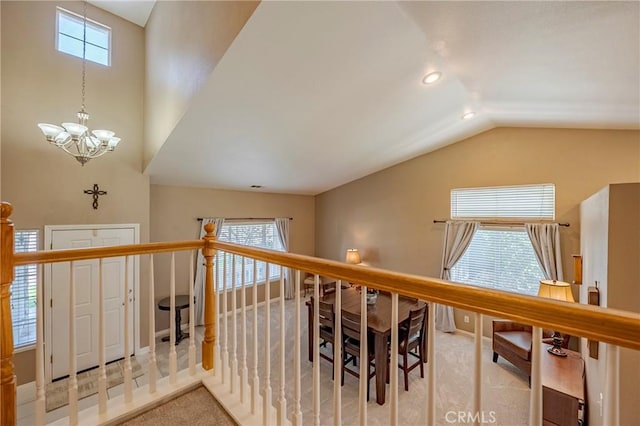 hall with an inviting chandelier, vaulted ceiling, carpet flooring, and a wealth of natural light