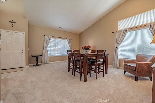 dining space with visible vents, high vaulted ceiling, carpet, tile patterned flooring, and baseboards