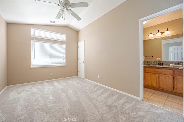 unfurnished room featuring a ceiling fan, visible vents, baseboards, vaulted ceiling, and light colored carpet