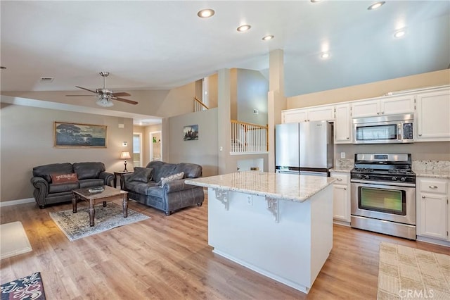 kitchen featuring white cabinetry, light stone counters, appliances with stainless steel finishes, and a center island