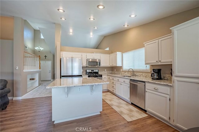 kitchen with a sink, light stone countertops, a kitchen island, and stainless steel appliances