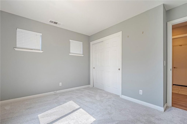 unfurnished bedroom with visible vents, a closet, carpet floors, and baseboards