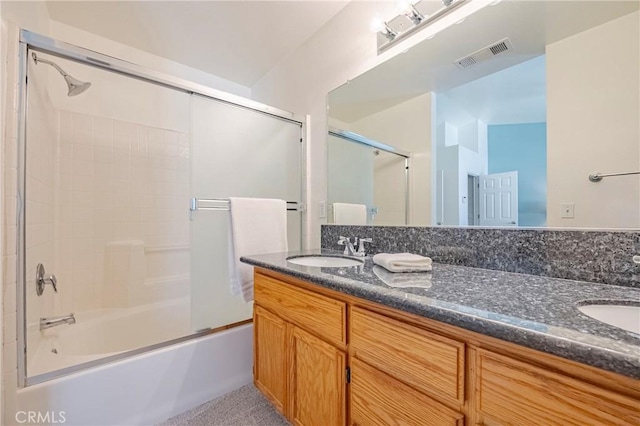 full bath with double vanity, visible vents, combined bath / shower with glass door, and a sink