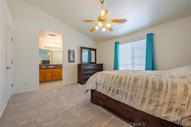 bedroom with visible vents, light colored carpet, lofted ceiling, ensuite bathroom, and a ceiling fan