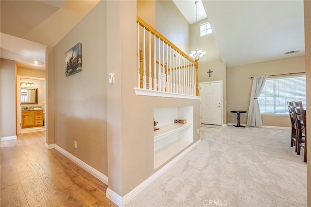 corridor with a notable chandelier, visible vents, baseboards, and carpet floors