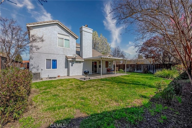 rear view of house with a patio area, a fenced backyard, a lawn, and a chimney