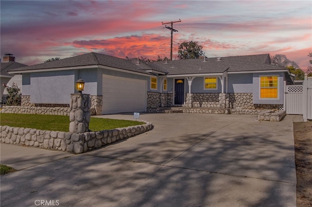 single story home featuring an attached garage, fence, stucco siding, stone siding, and driveway