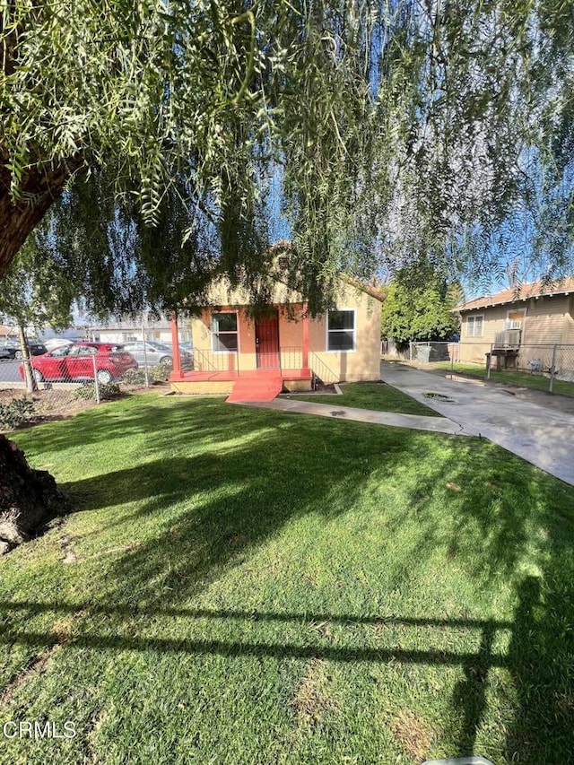 view of front of house featuring a front yard, fence, and stucco siding