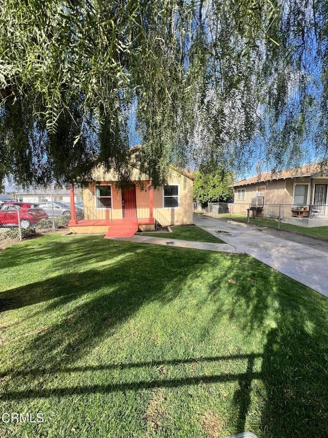 view of front of home featuring stucco siding, a front lawn, and fence