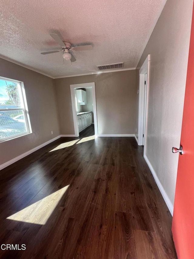 spare room with a ceiling fan, wood finished floors, visible vents, baseboards, and a textured ceiling