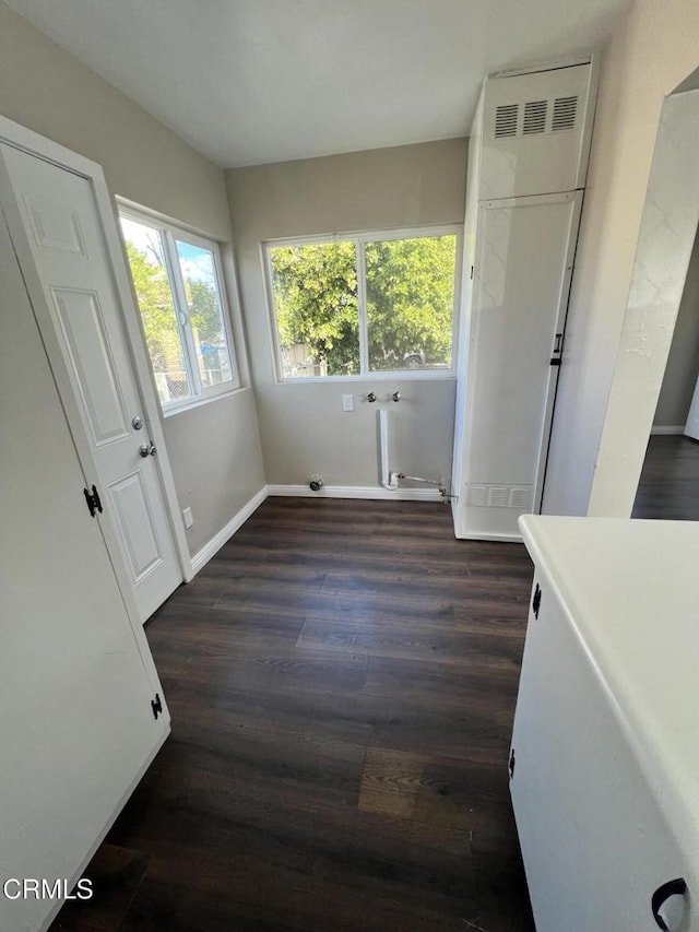 unfurnished dining area featuring dark wood finished floors and baseboards