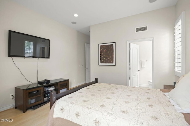 bedroom with multiple windows, light wood-type flooring, visible vents, and ensuite bathroom