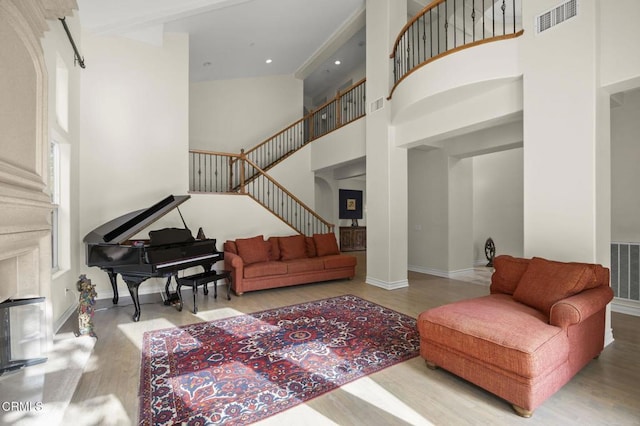 living area featuring visible vents, wood finished floors, a towering ceiling, and stairway
