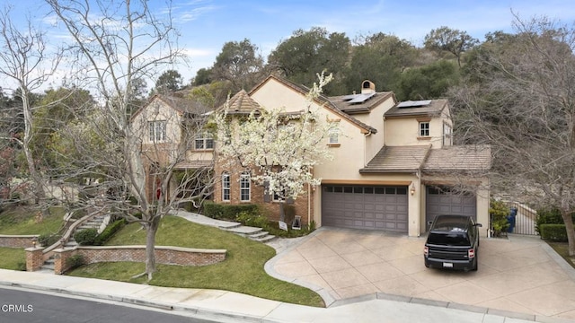 view of front of property featuring an attached garage, driveway, stucco siding, roof mounted solar panels, and a chimney