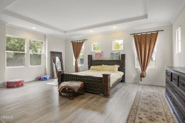 bedroom featuring a tray ceiling, light wood finished floors, crown molding, and recessed lighting