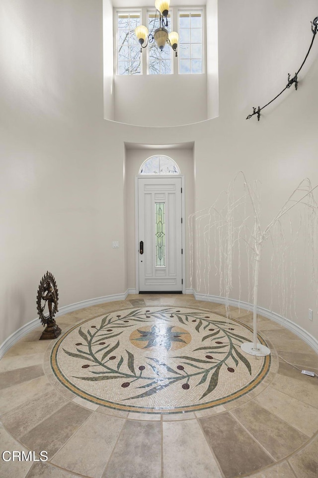 entryway with a chandelier, baseboards, and a towering ceiling