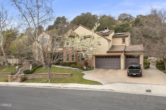 traditional-style home featuring a gate, a garage, stucco siding, concrete driveway, and solar panels