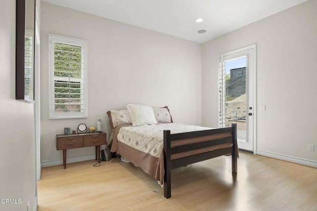 bedroom with light wood finished floors, multiple windows, baseboards, and access to exterior