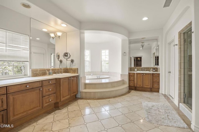 bathroom with visible vents, a bath, a sink, a shower stall, and two vanities
