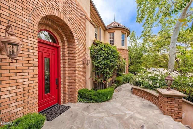 doorway to property featuring stucco siding and brick siding