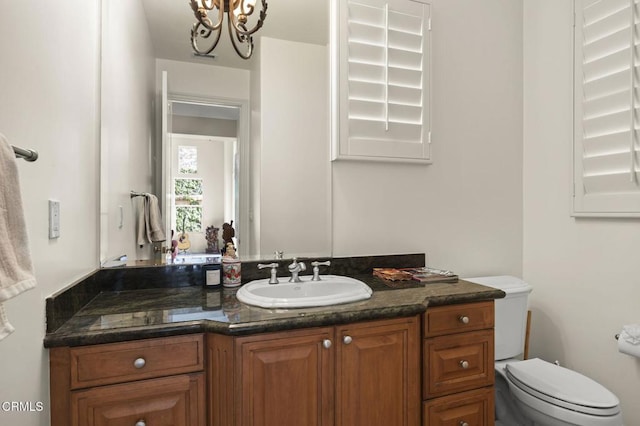 half bathroom featuring vanity, toilet, and a chandelier