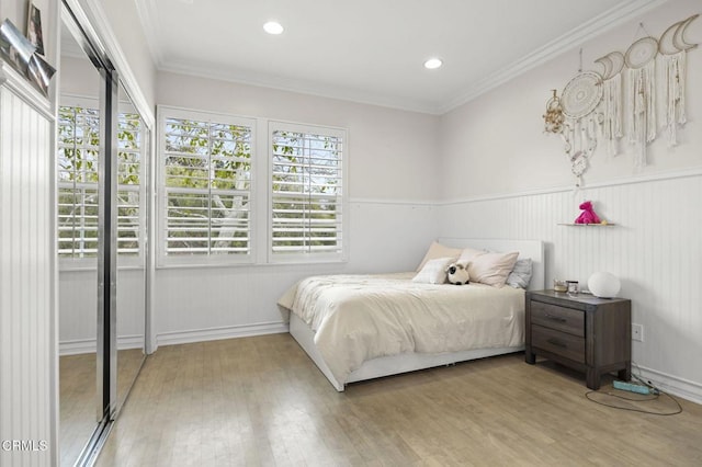 bedroom featuring crown molding, a wainscoted wall, and wood finished floors