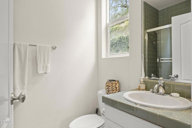bathroom with toilet, vanity, and tiled shower