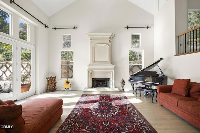 living area featuring high vaulted ceiling, a fireplace with raised hearth, and wood finished floors